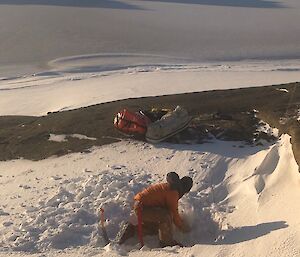 An expeditioner digs in the snow to create a level tent pitch