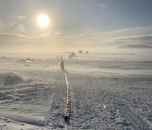 Blowing snow with expeditioners in the distance packing up a hose