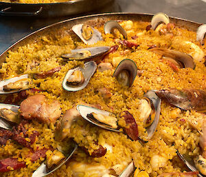 Two big paella dishes waiting on bench to be served