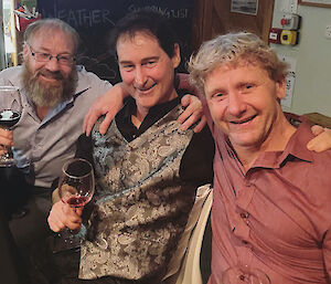 Three expeditioners holding wine glasses and smiling