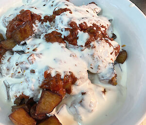 Bowl of fried potato cubes covered in tomato and cream sauce