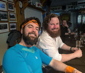 Two expeditioners smiling at the camera, one wearing tennis sweatbands