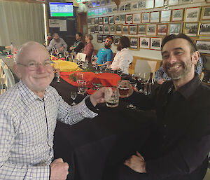 Two expeditioners with beer glasses and saying cheers to camera