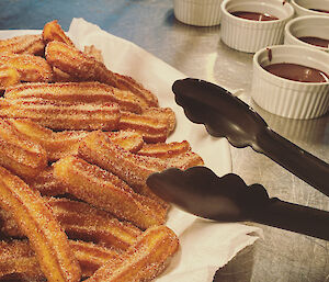 Bowl of churros with small bowls of chocolate sauce behind
