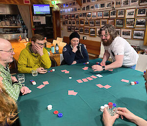 People sitting around a table with cards and poker chips