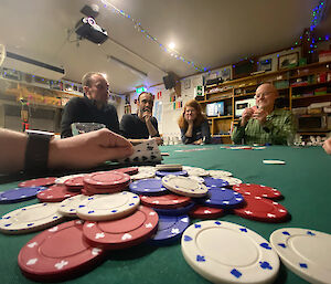 Pile of poker chips and people sitting around the table