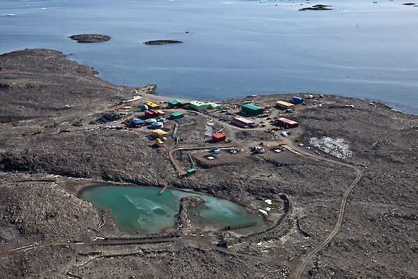 Aerial view of green-coloured tarn behind Davis station buildings.