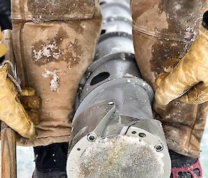 An expeditioner holds a large ice core between his legs