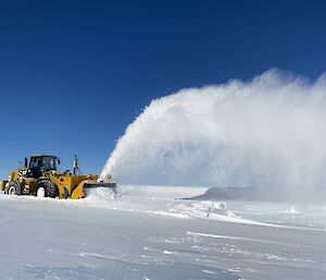 An Øveraasen snow blower on the runway with a plume of snow flying in the air