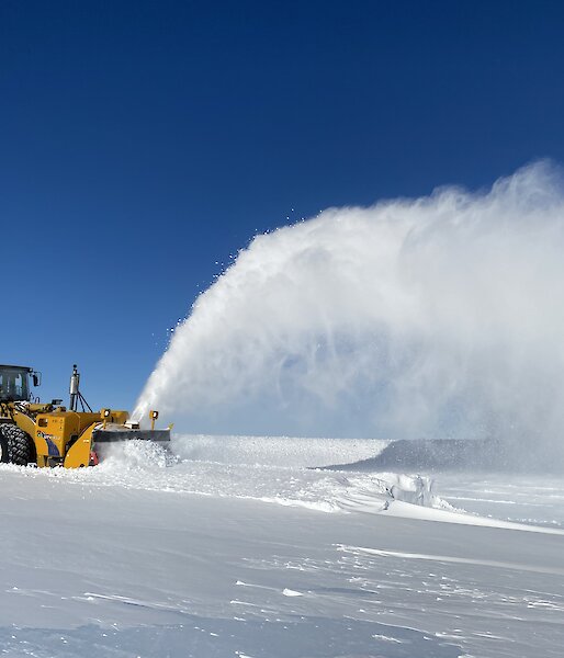 An Øveraasen snow blower on the runway with a plume of snow flying in the air