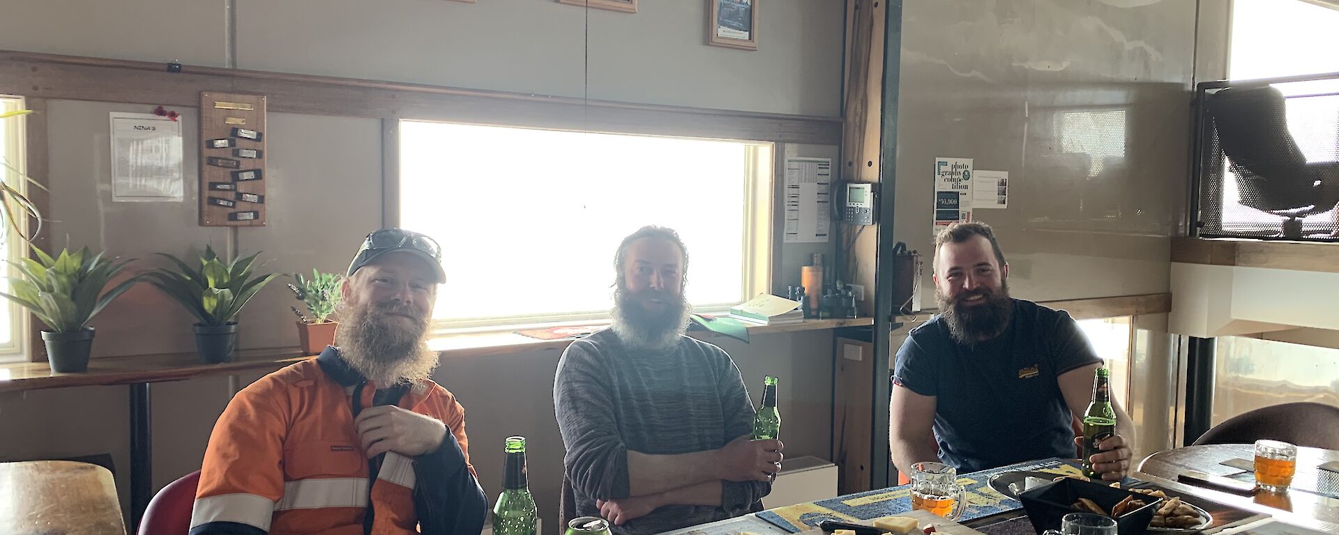 Three plumbers sitting at a table drinking beer