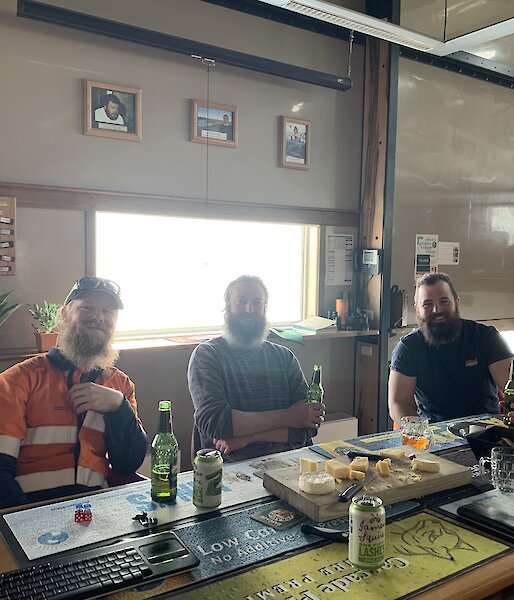 Three plumbers sitting at a table drinking beer