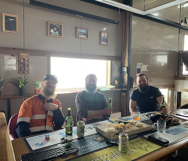 Three plumbers sitting at a table drinking beer