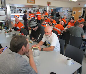 Casey expeditioners in high vis shirts enjoying a break in the mess.