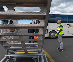 Passengers wearing masks get off a bus and climb stairs to an aircraft.