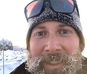 Head shot of expeditioner wearing a beanie and sunglasses on his head with frost on his beard