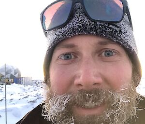 Head shot of expeditioner wearing a beanie and sunglasses on his head with frost on his beard