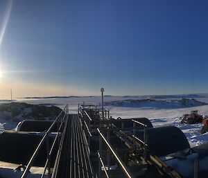 Looking out over the top of 6 fuel tanks, two tractors parked at the side, towards the horizon