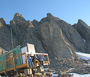 Expeditioners sit on the deck of Rumdoodle hut near Mawson