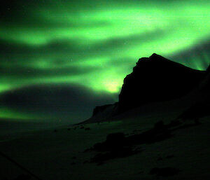 Green aurora against black mountains