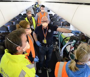 people wearing masks on plane with medical equipment