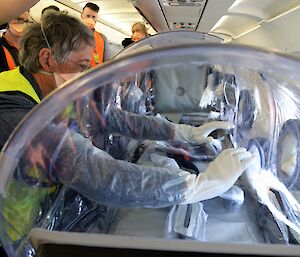 Man with hands in gloves in isolation chamber