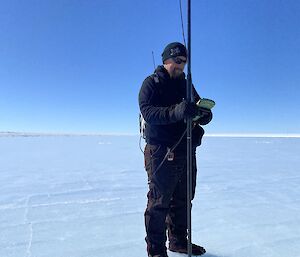 A man stands on the runway surface with testing equipment