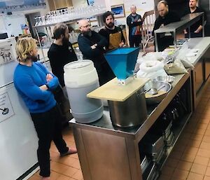 Expeditioners gathered around the station kitchen bench learning about brewing