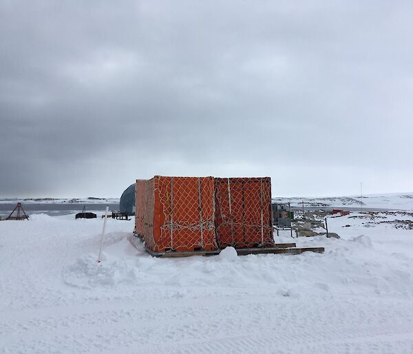 Two large red shipping containers tied up on pallets on the ice