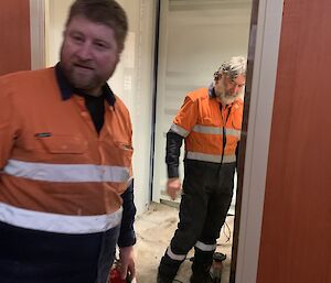 Two expeditioners in tradie uniforms working in one of the sheds