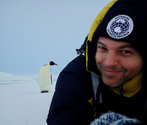 Man and penguin on the ice in Antarctica