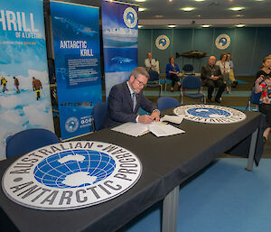 Man sits at table and signs paper