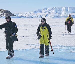 Three expeditioners walk towards camera over the sea ice