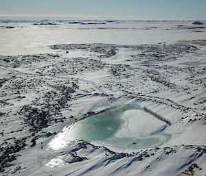 Aerial image of the snowy landscape with a lake visible in the middle of shot