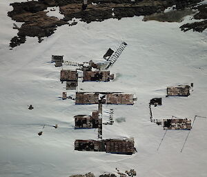 Aerial shot looking down on the roofs of the old buildings at Wilkes station, which are part buried in the snow