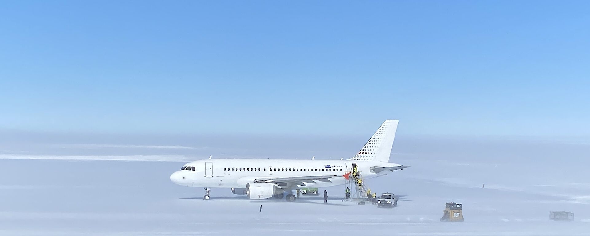 A319 Airbus sitting on the ice runway with support crew surrounding