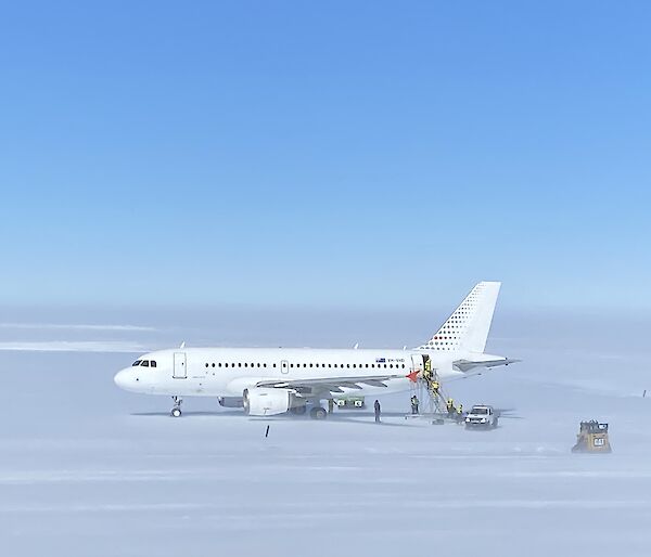 A319 Airbus sitting on the ice runway with support crew surrounding