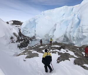 Expeditioners look close up at an iceberg veryclose to shore in the sea ice