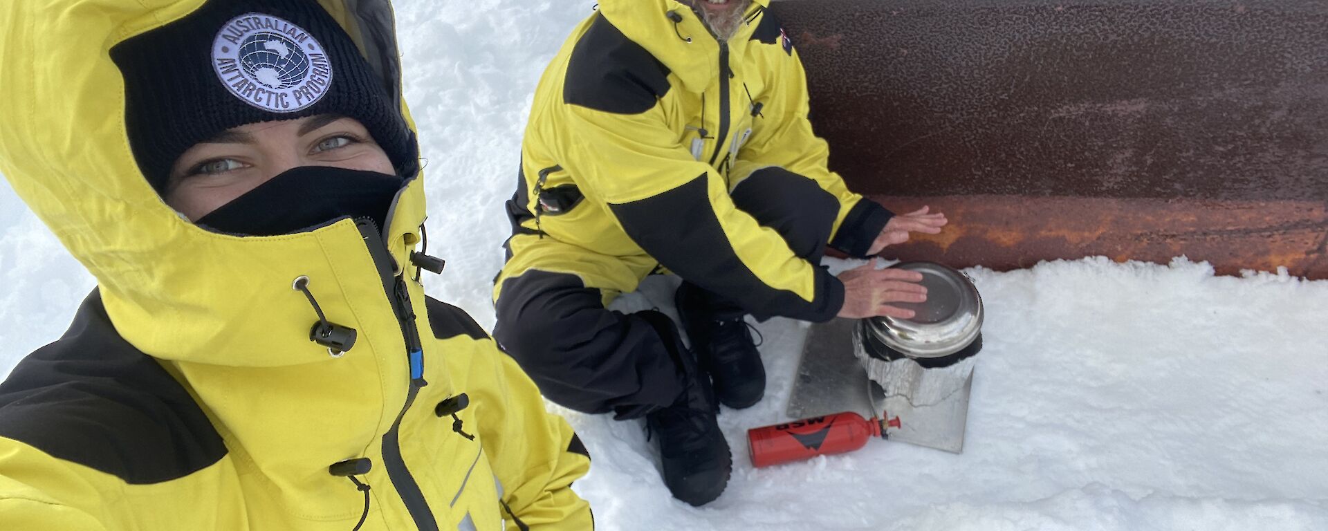 Two expeditioners preparing a meal in the snow.