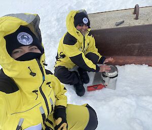 Two expeditioners preparing a meal in the snow.