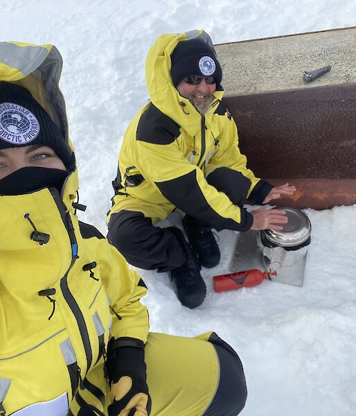 Two expeditioners preparing a meal in the snow.