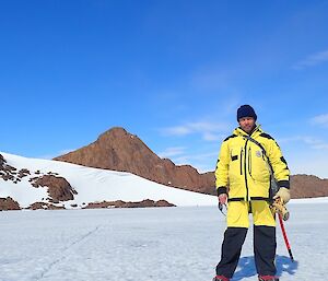 An expeditioner standing on the sea ice with the mountains in the background
