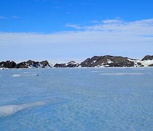 A plateau of sea ice with mountains on the horizon