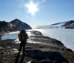 An expeditioner in the foreground looking out over a frozen Hanging Lake