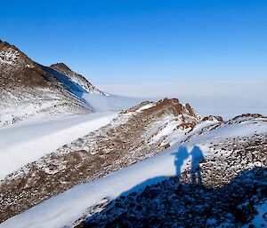 Two expeditioners shadows cast on to a snowy ridge