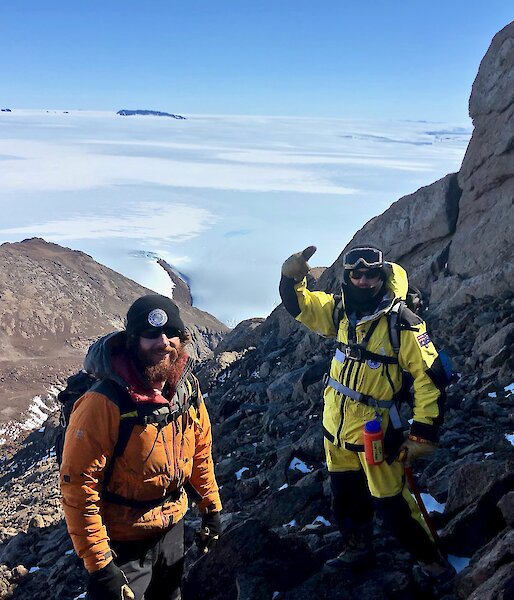 Three expeditioners smiling to camera near the summit of the mountain.  Glacier and snow below