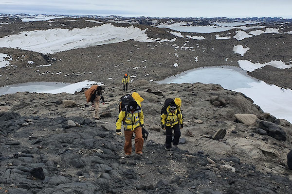 group of people walking in low rocky snowy hills