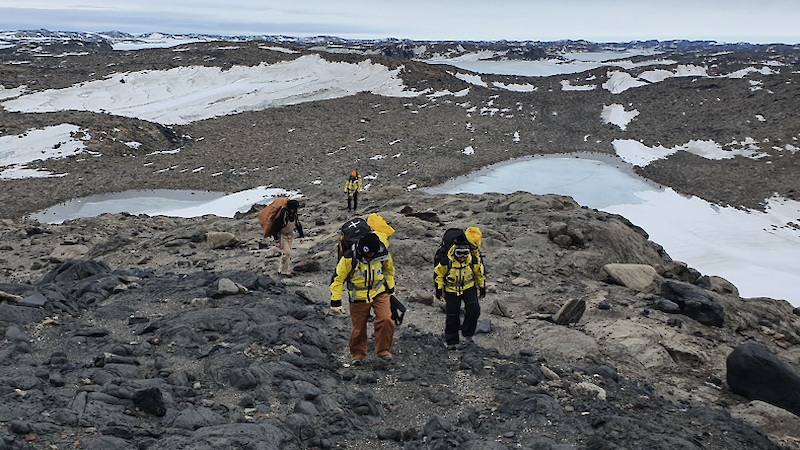 group of people walking in low rocky snowy hills