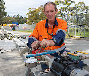 Brad in the Australian Antarctic Division’s works yard turning a hose valve, with 200 metre lengths of hose stretching into the background.