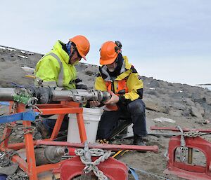 Two people connect hoses from ship to shore.